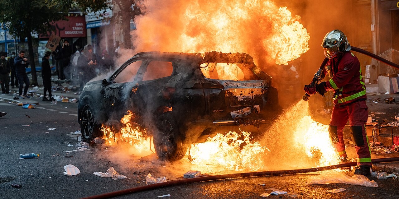 Firefighters extinguish a burning car during Paris riots preview image